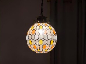 Un luminaire suspendu de forme sphérique, orné d’un motif en mosaïque.