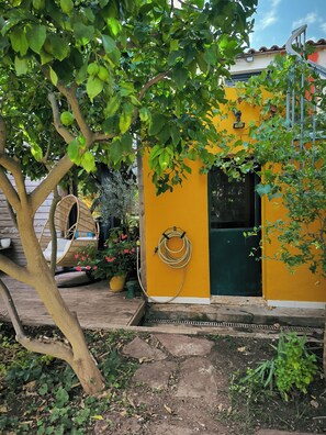 A yellow house with a green door, a hanging garden hose, and a wicker swing chair. - House with a lovely garden that's not visible from the street (Sète)