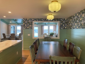 A dining area with a long table and chairs, a window with curtains, and a ceiling light fixture. - Skaneateles country home just a short walk to downtown  (Skaneateles)
