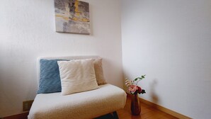 A cozy room with a sofa, two pillows, and a vase with flowers.