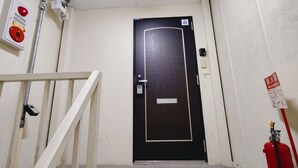 A black door with a fire extinguisher and a fire alarm on the wall.