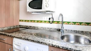 A kitchen with a built-in microwave, stainless steel sink, and granite countertop. - Peaceful Apartment Close to the Coast (Conil de la Frontera)