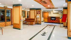 Un hall d’hôtel comprenant un comptoir d’accueil, un café et un escalier.