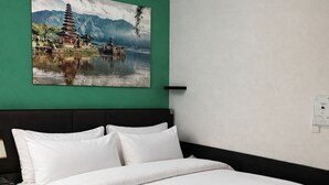A hotel room with a large bed, white bedding, a green accent wall, and a painting of a traditional building by a lake. - Corner view Residence | Panorama balcony (Koblenz)