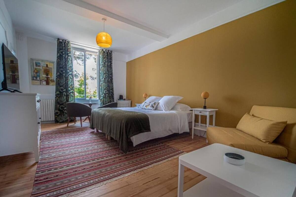 A bedroom with a bed, a sofa, a coffee table, and a desk.