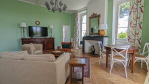 Una sala de estar con sofá, televisión, aparador de madera y chimenea.