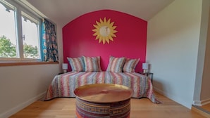 Un dormitorio con una cama, una mesa redonda y una decoración de sol en la pared.