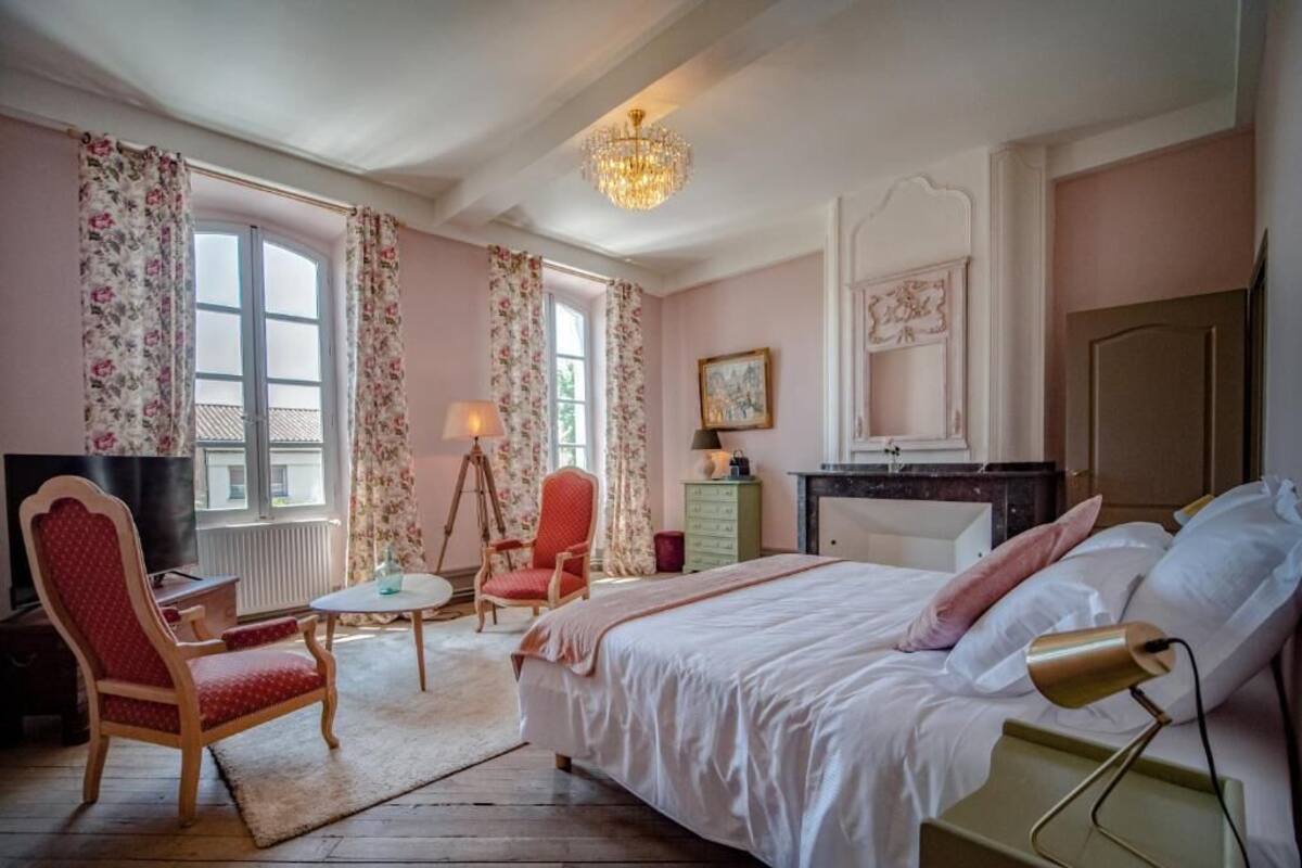 A bedroom with a bed, a chair, a desk, a dresser, and a window with curtains.