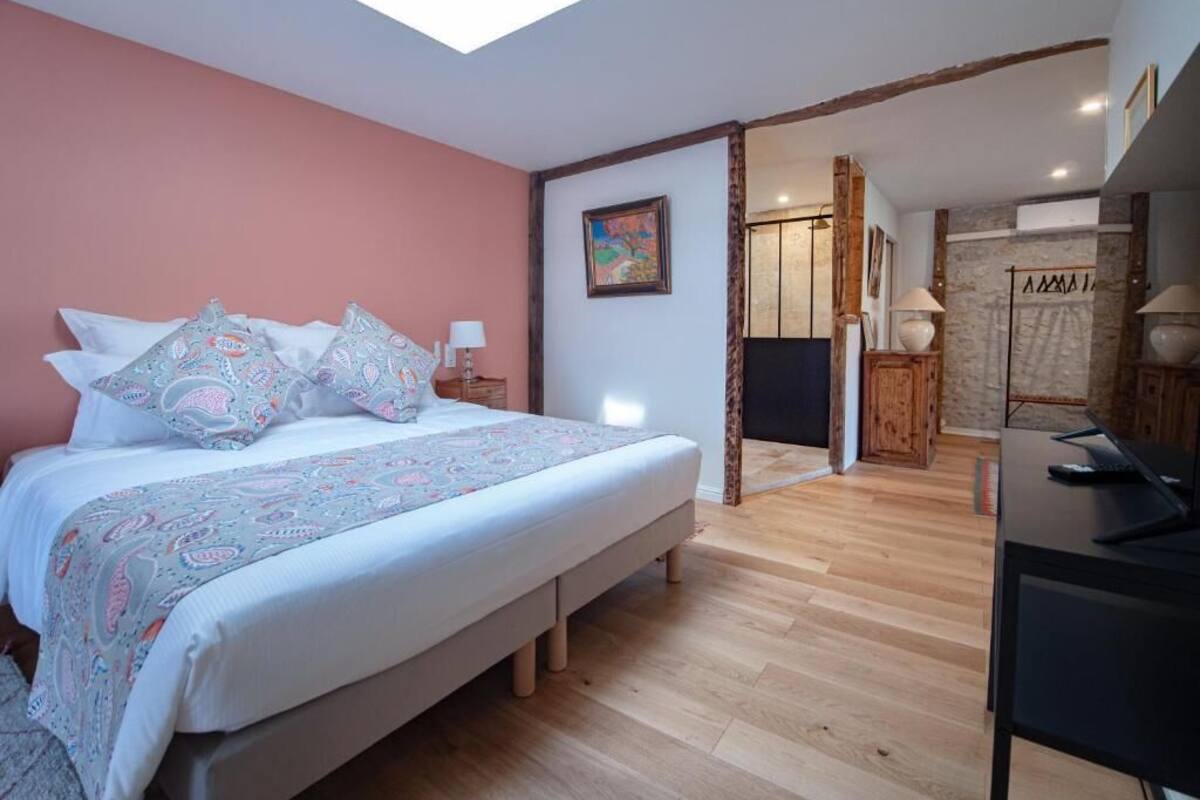 A bedroom with a large bed, a skylight, a desk, and a wardrobe.