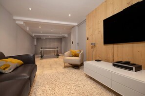 Ein modernes Wohnzimmer mit einer Couch, einem Sessel, einem Fernseher und einem weißen Schrank.
