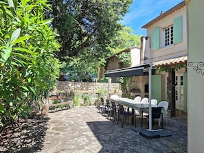 A patio with outdoor seating, a stone wall, and a building with green shutters.