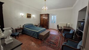 Een slaapkamer met een groot bed, een houten garderobe, een televisie en een raam.