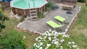 A backyard with a hot tub, wooden deck, two green chairs, and a white umbrella. - COUNTRY HOUSE in FONROQUE 2km from BASTIDE D'EYMET (Fonroque)