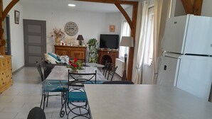 A spacious kitchen with a large island, wooden beams, a dining area with chairs, a television, and a refrigerator. - COUNTRY HOUSE in FONROQUE 2km from BASTIDE D'EYMET (Fonroque)
