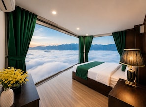 A hotel room with a large window, a bed, a bedside table, and a lamp. - Cloud Chaser Hotel (Sa Pa)