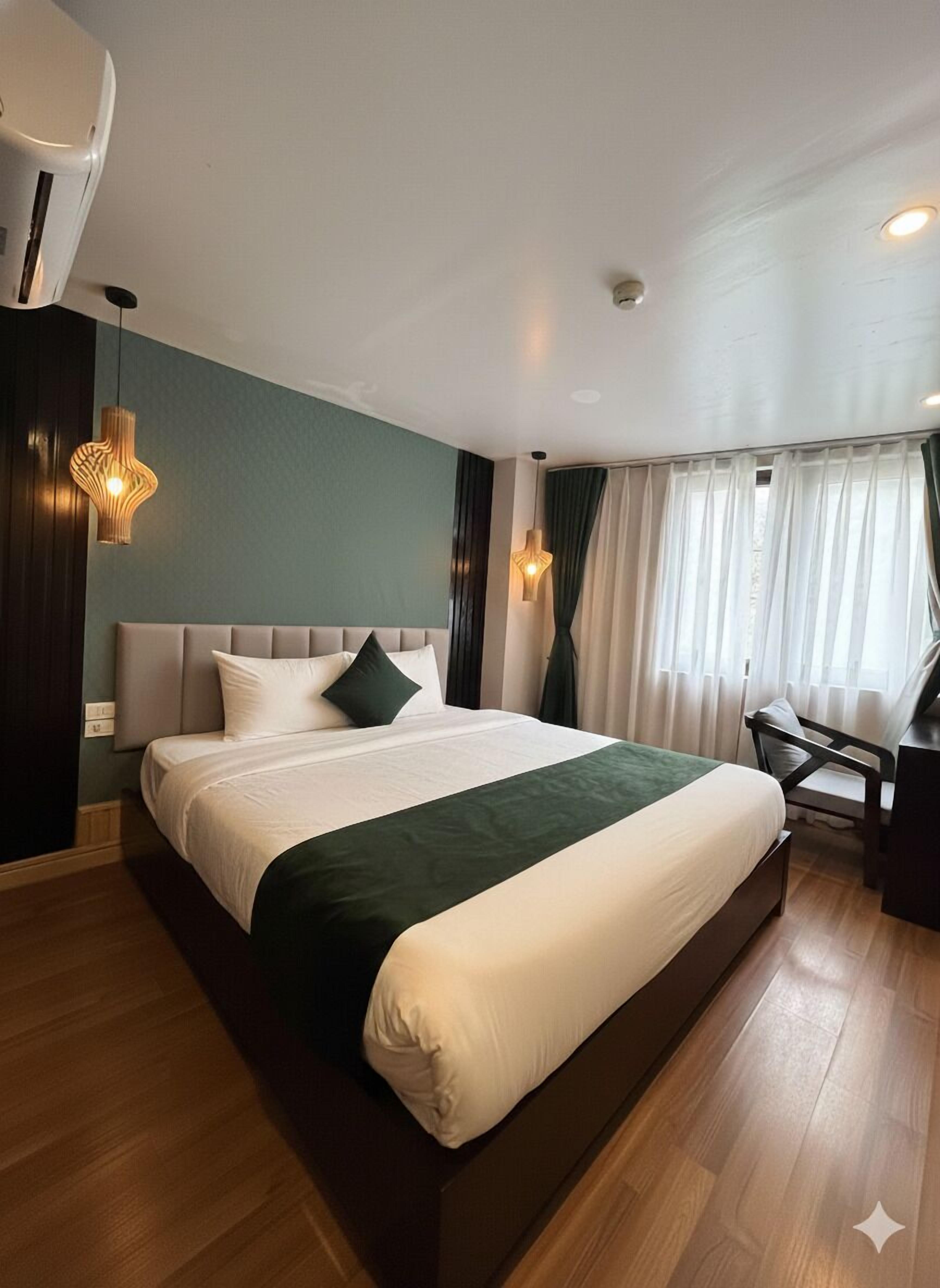 A modern hotel room with a large bed, a desk, and a chair.