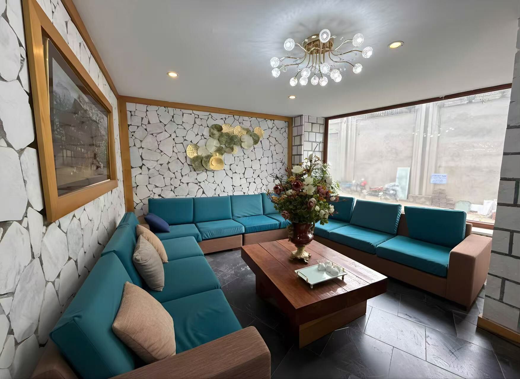 A modern living room with teal sofas, a wooden coffee table, and a decorative vase.
