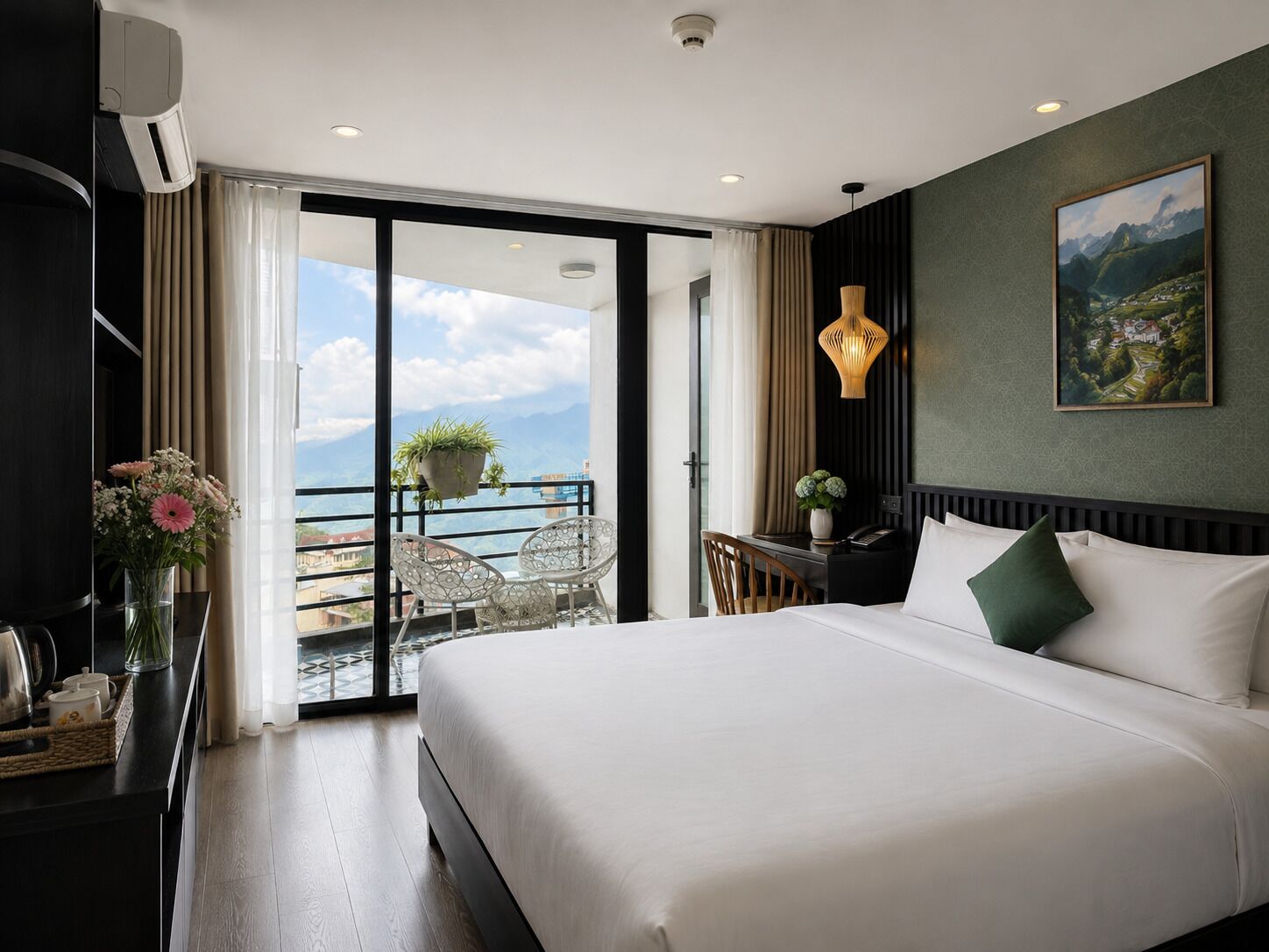 A hotel room with a large bed, a desk with a chair, a balcony with a view, and a painting on the wall.
