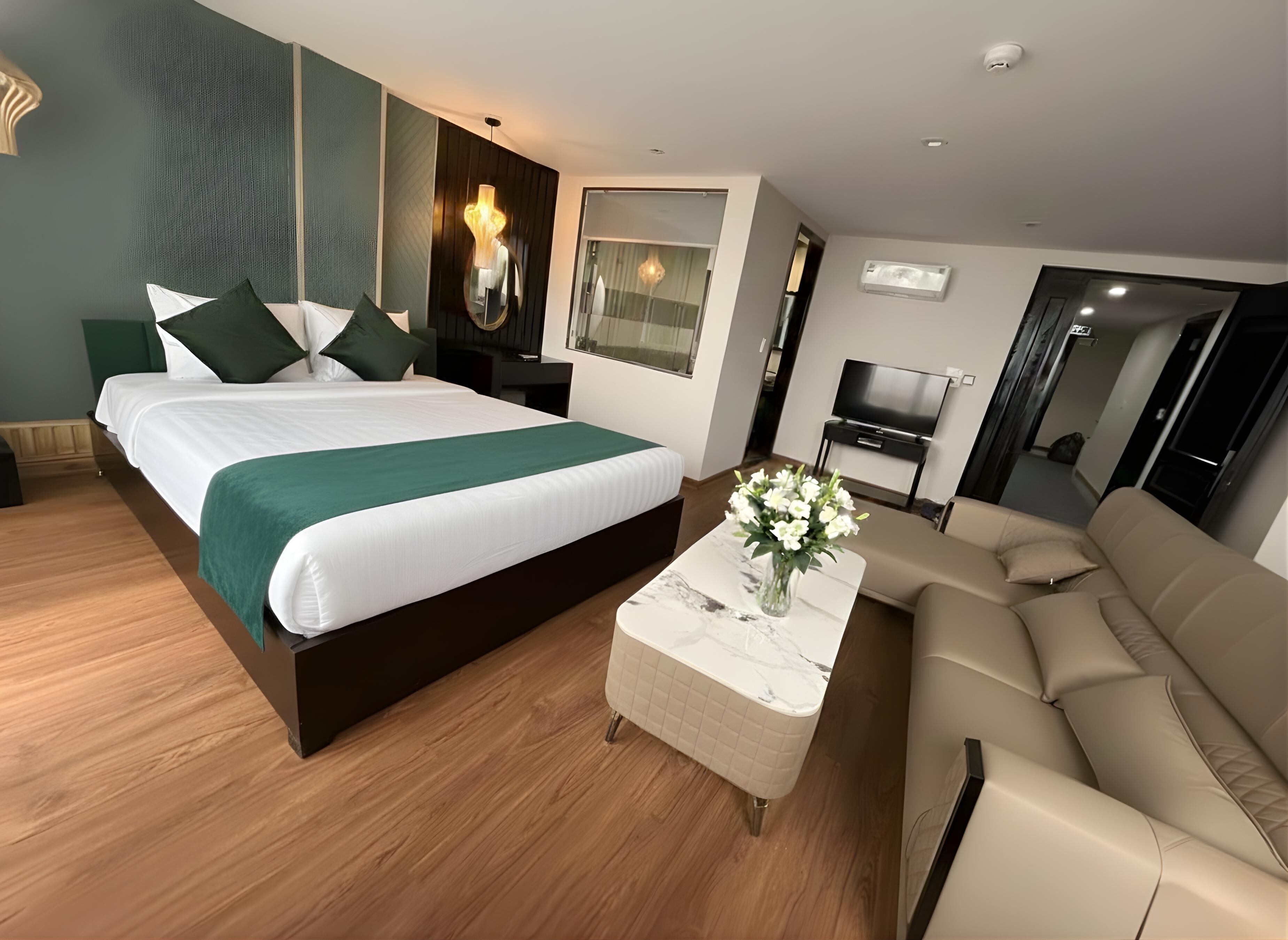Une chambre d’hôtel moderne avec un grand lit, un canapé, une table basse en marbre et un téléviseur.