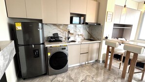 Une cuisine moderne équipée d’un lave-linge encastré, d’un évier et d’un four à micro-ondes.
