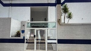 A hotel entrance with a gated entrance, a sign above the door, and a palm tree to the right. - FOR RENT!!! "Apartment in Praia Grande, Canto do Forte" (Praia Grande)