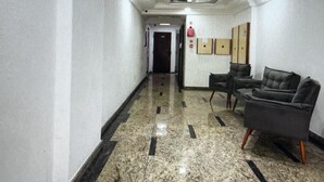 A hallway with a polished marble floor, a reception desk, and two dark armchairs. - FOR RENT!!! "Apartment in Praia Grande, Canto do Forte" (Praia Grande)