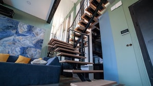 A modern living room with a blue sofa, wooden floating stairs, and a marble-patterned wall. - Private Wellness Residence with Heated Pool (Antalya)