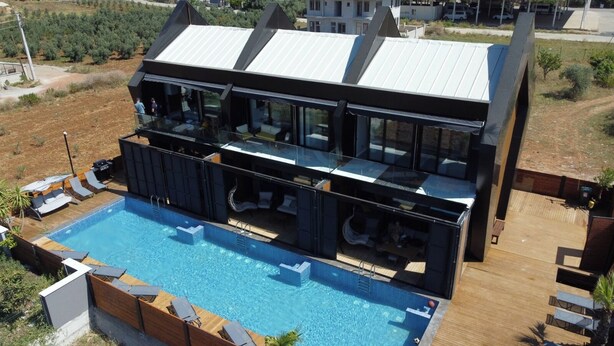 A modern two-story building with a swimming pool, outdoor seating, and a view of the surrounding landscape. - Private Wellness Residence with Heated Pool (Antalya)