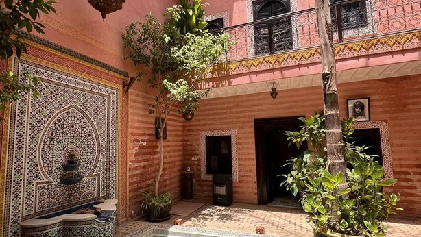A courtyard with a swimming pool, potted plants, and a decorative wall. - Riad de Charme, 5 minutes Place Jemaa El Fna (Marrakech)