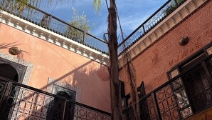A building with a balcony, ornate railings, and a palm tree. - Riad de Charme, 5 minutes Place Jemaa El Fna (Marrakech)
