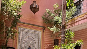 A courtyard with a decorative fountain, a pool, and potted plants. - Riad de Charme, 5 minutes Place Jemaa El Fna (Marrakech)