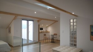 A modern interior with a dining area, kitchen, and a glass railing overlooking a balcony. - Lovely studio with modern comforts and exceptional view (Calvi)