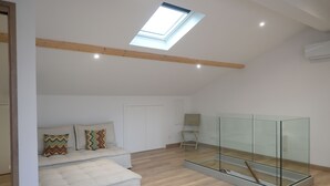 A modern living room with a loft bed, a glass enclosure, and a skylight. - Lovely studio with modern comforts and exceptional view (Calvi)