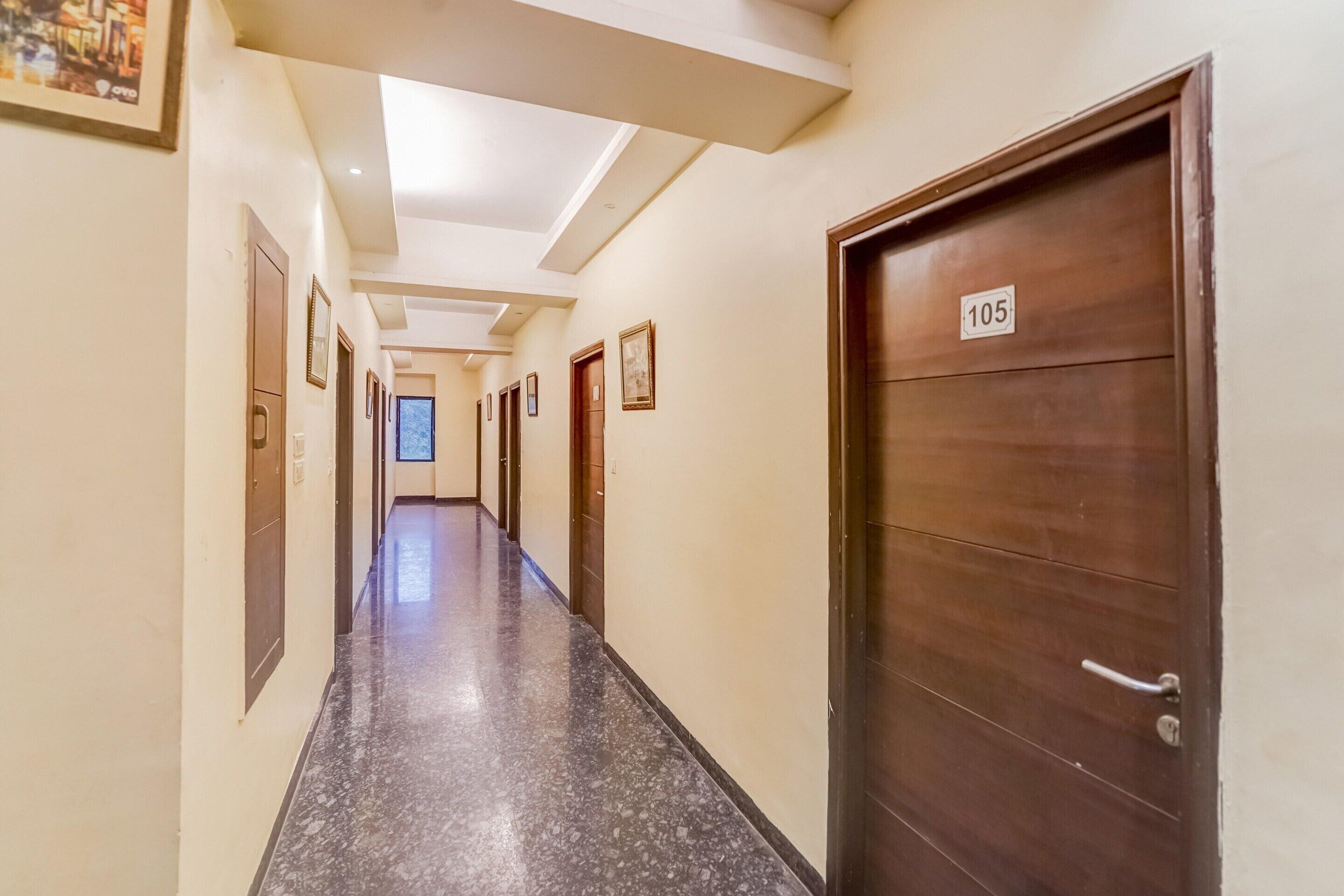 A long, narrow hallway with a polished floor, wooden doors, and a ceiling with recessed lighting.