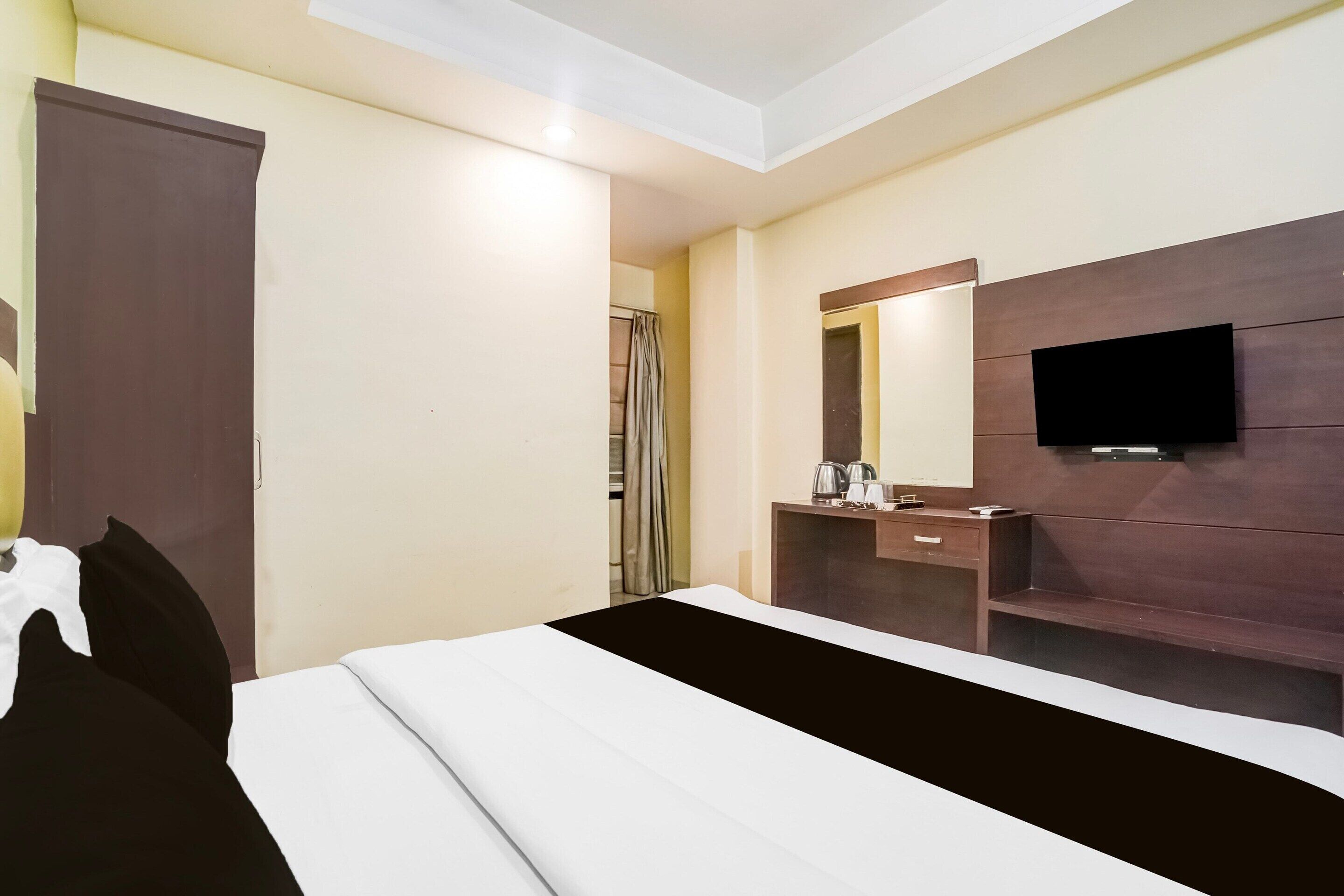 Una habitación de hotel con una cama, un aparador, un espejo y un televisor.