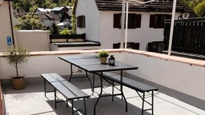 A rooftop terrace with a table and benches, a potted plant, and a view of houses in the background. - Odw Homes – Charming Home in Gorxheimertal (Gorxheimertal)