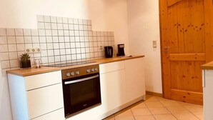 A kitchen with white cabinets, a black oven, and a wooden door. - Odw Homes – Charming Home in Gorxheimertal (Gorxheimertal)