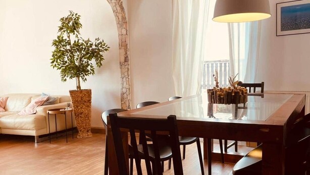 A dining area with a wooden table, chairs, a hanging light fixture, a potted plant, and a stone wall. - Odw Homes – Charming Home in Gorxheimertal (Gorxheimertal)