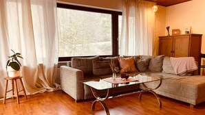 Ein gemütliches Wohnzimmer mit einer Couch, einem Glastisch und einem Holzschrank.