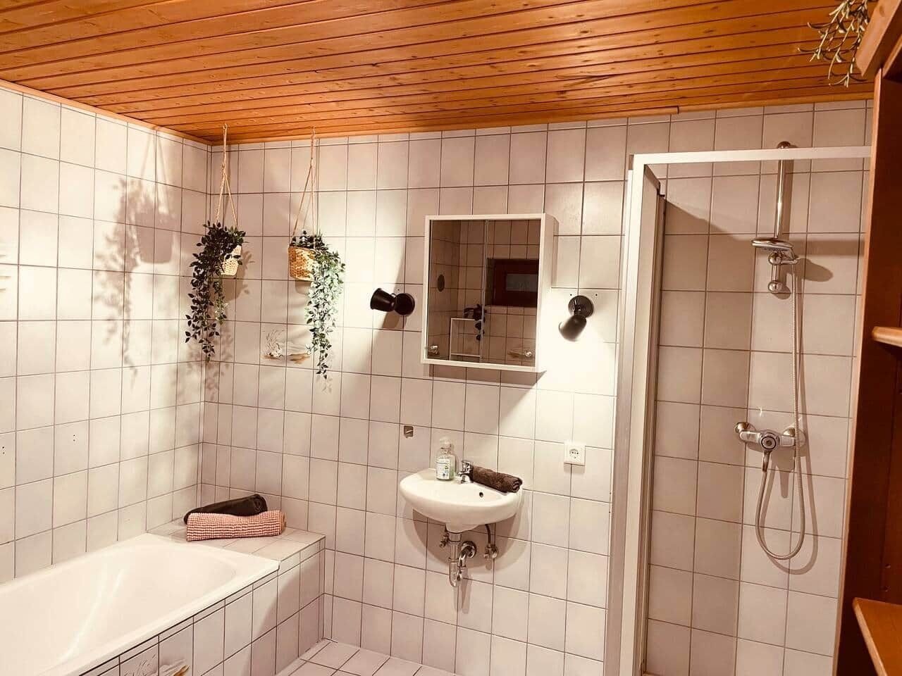 Un baño con un lavamanos blanco, un espejo y una ducha.