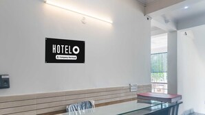 A hotel reception desk with a sign that reads "HOTELO Company Serviced." - Hotel O The Grand Venice Mall (Noida)