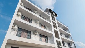 A multi-story hotel with a modern architectural design, featuring balconies on each floor and a prominent hotel sign. - Hotel O The Grand Venice Mall (Noida)