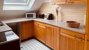 Een keuken met houten kastjes, een magnetron, een koffiezetapparaat en een dakraam.