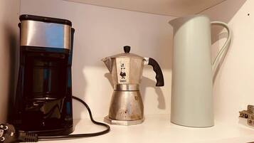 A kitchen shelf with a coffee maker, a kettle, and a power cord.