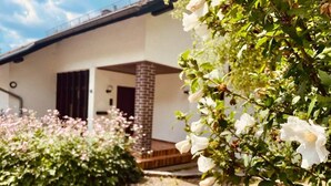 Uma casa com coluna de tijolo, deck de madeira e calçada pavimentada.