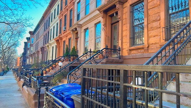 A row of brownstone buildings with ornate iron railings and blue trash bins. - Beautiful Spacious 3BR/3BA Bed-Stuy Brownstone Duplex, King Bed, Heated Floors (Brooklyn)