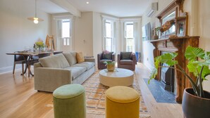 A spacious living room with a sofa, armchairs, a coffee table, and a fireplace. - Beautiful Spacious 3BR/3BA Bed-Stuy Brownstone Duplex, King Bed, Heated Floors (Brooklyn)