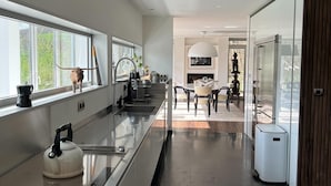 Una cocina moderna con una encimera larga, electrodomésticos de acero inoxidable y vistas al comedor.