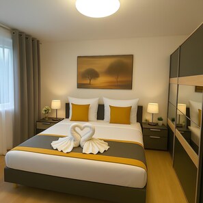 A hotel room with a large bed, two bedside tables with lamps, a painting of trees, and a mirror on the wall. - StadtLicht Apartment with Balcony (Koblenz)