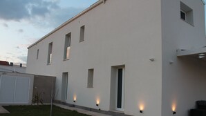 En moderne bygning med en flad facade, mange vinduer og udvendig belysning.